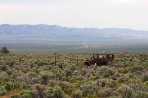 rusty old car in field with mountain background