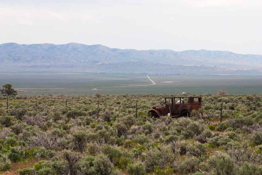 rusty old car in field with mountain background