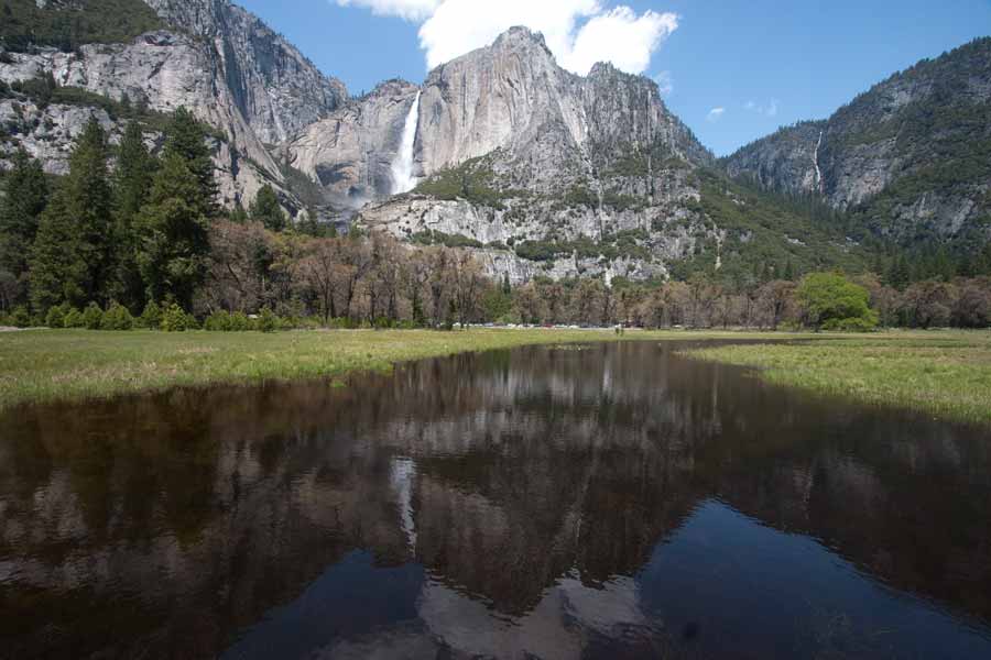 river flows through the meadow with waterfall in background in
