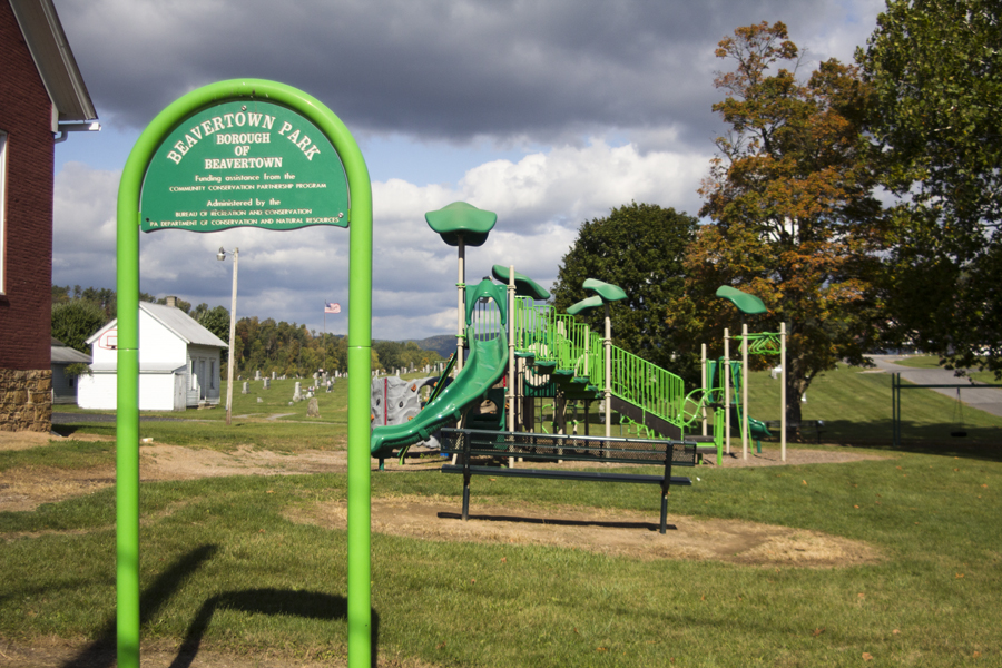 sign for Beavertown Park with bench and playground behind it