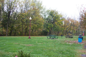 picnic tables, a street light, trash can, and a grill