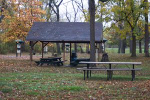 pavilion with four picnic tables and a trash can and a picnic table in front of it