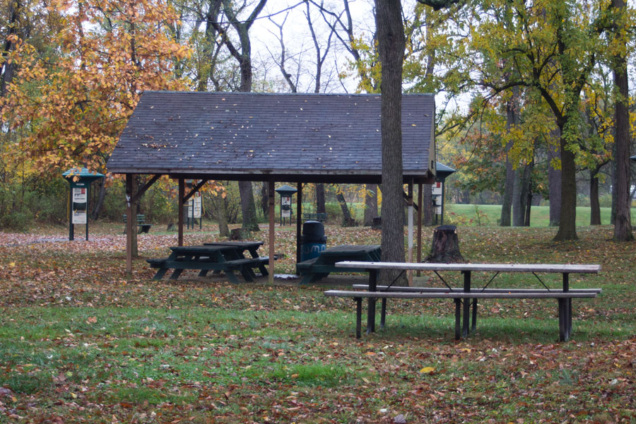 pavilion with four picnic tables and a trash can and a picnic table in front of it