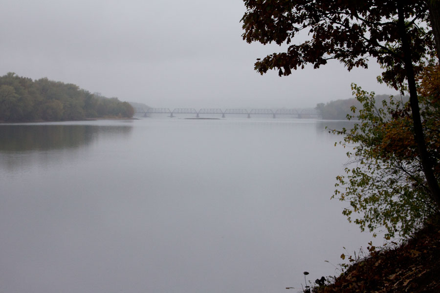a foggy view of a bridge downriver