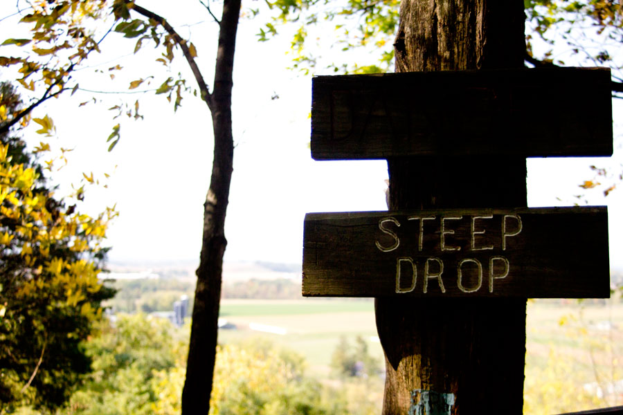view of farmland below steep drop sign
