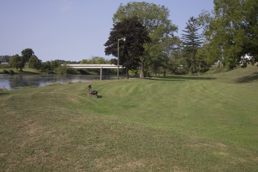 green space beside the stream and a bench
