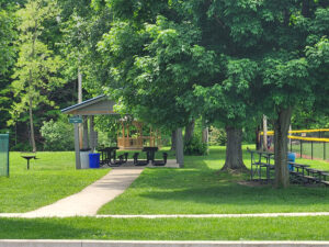 gazebo behind a pavilion with picnic tables.