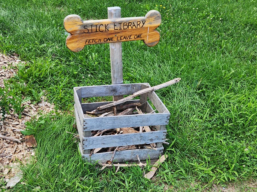 The sign says "stick library: fetch one leave one."