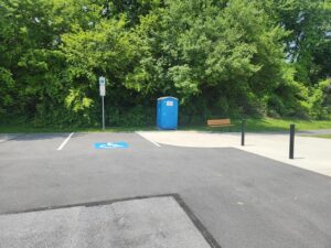 handicap parking space, port-a-potty, and bench.