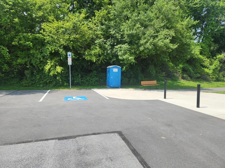 handicap parking space, port-a-potty, and bench.