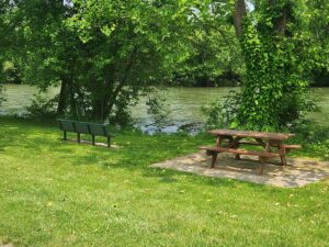 picnic table and bench beside river.
