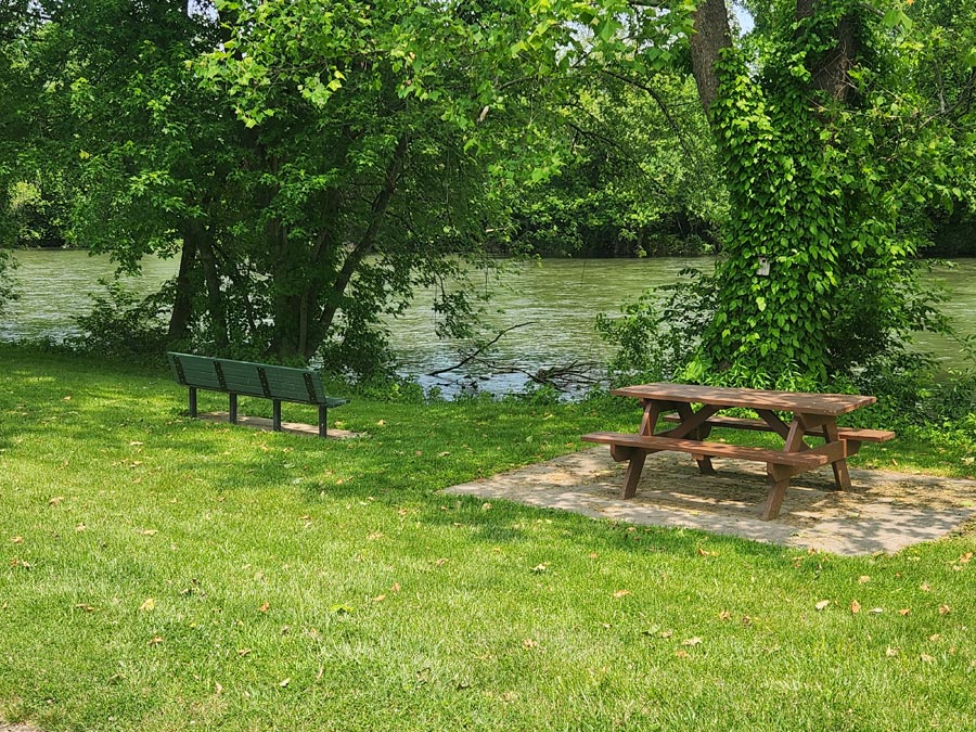 picnic table and bench beside river.